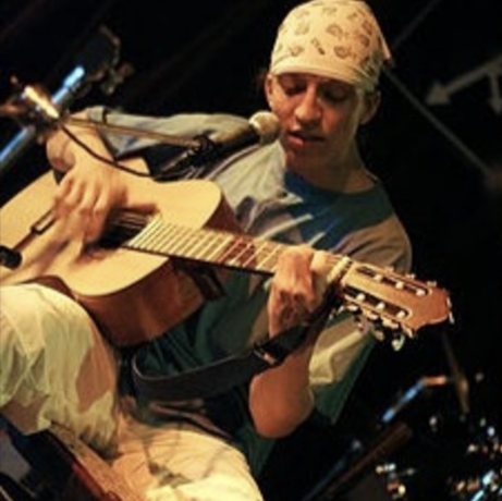 Mladý Dali hraje v hudebním bazaru v Ostravě na kytaru s šátkem s obrázky piva
